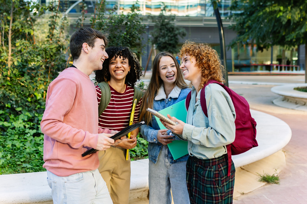 مجموعة من الطلاب الشباب يضحكون معًا في الحرم الجامعي أثناء دراسة اللغة الإنجليزية في بريطانيا