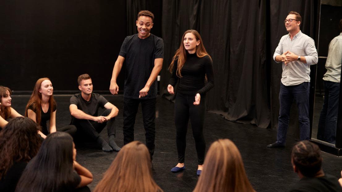Teacher With Male And Female Drama Students At Performing Arts School