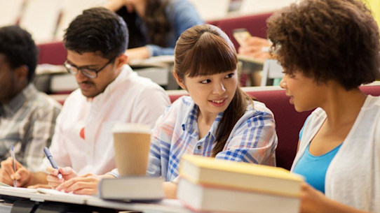 International students discussing notes in a university lecture