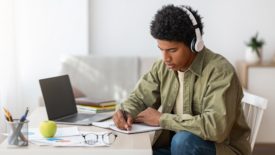 Focused black student writing down information