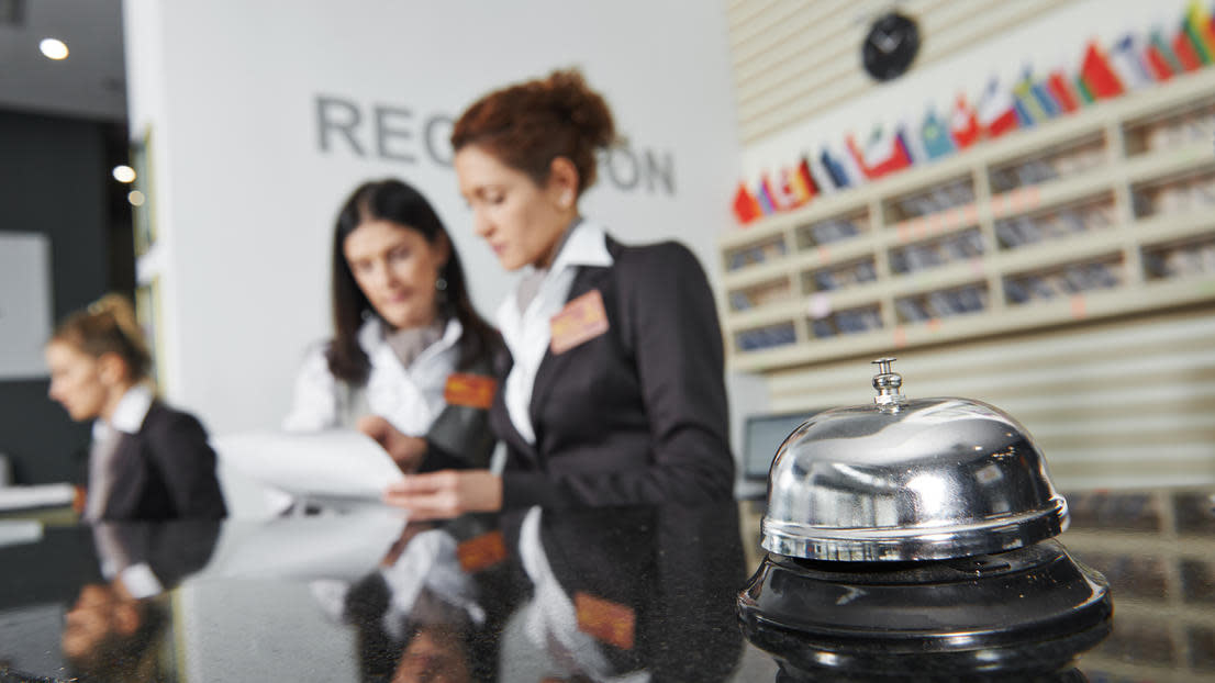 Three workers at hotel reception with bell on desk