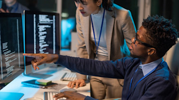 Two young intercultural colleagues discussing coded data