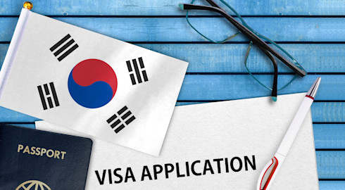 Graphic representing South Korea visa applications, featuring the country's flag, a passport, application form, pen, and eyeglasses on a blue table.