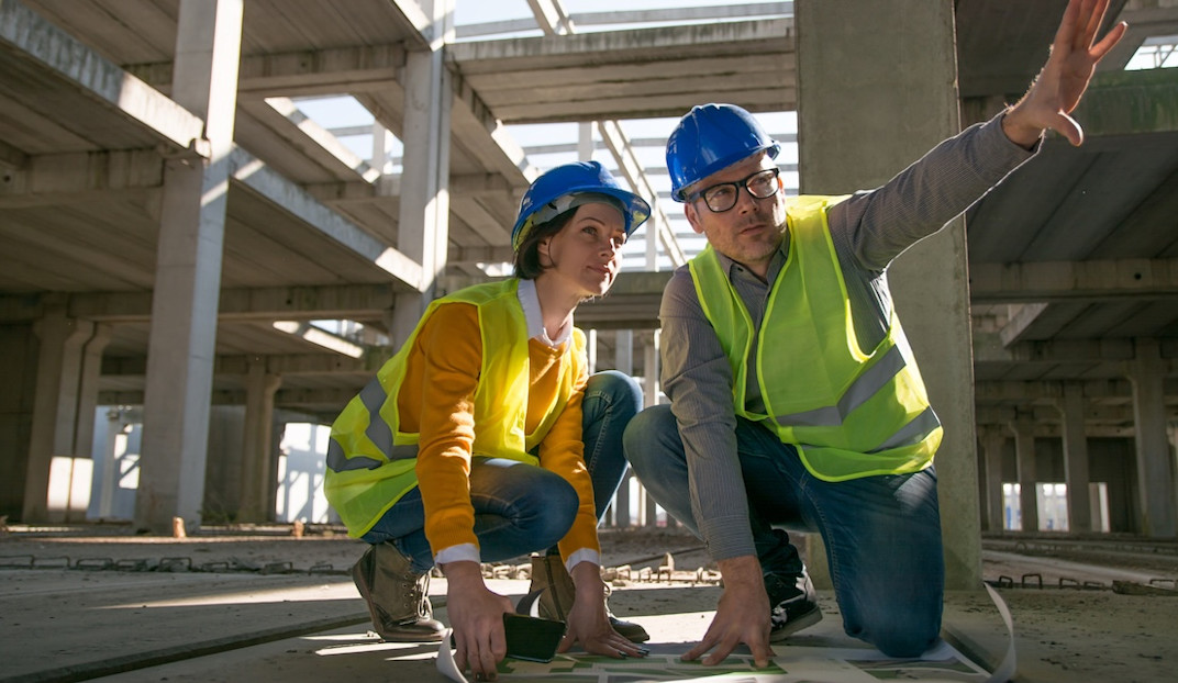 Two surveyors kneeling on the floor and discussing project