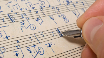 Person writing music notations onto manuscript paper