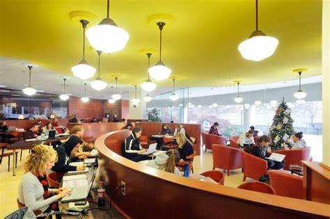 Several students sit talking and working on laptops in the well-lit Virginia Tech library cafe