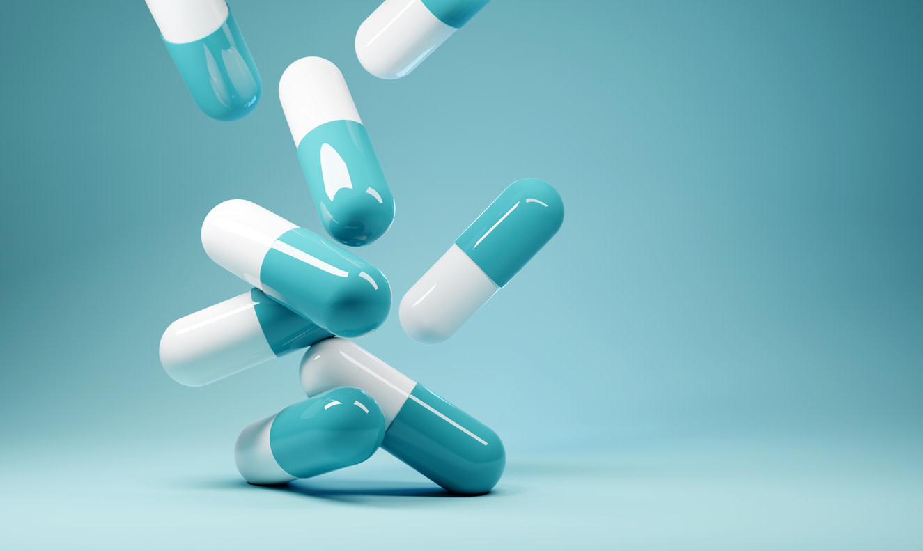 A close-up view of eight blue-and-white antibiotic pill capsules, all of which are falling