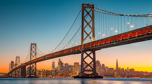 The side of Oakland Bay Bridge at dusk, viewed from San Francisco Bay towards the city
