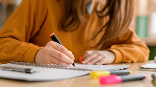 Young female university student highlighting notes in a notebook 