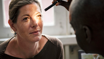 Blonde woman getting an eye examination with a small light tool