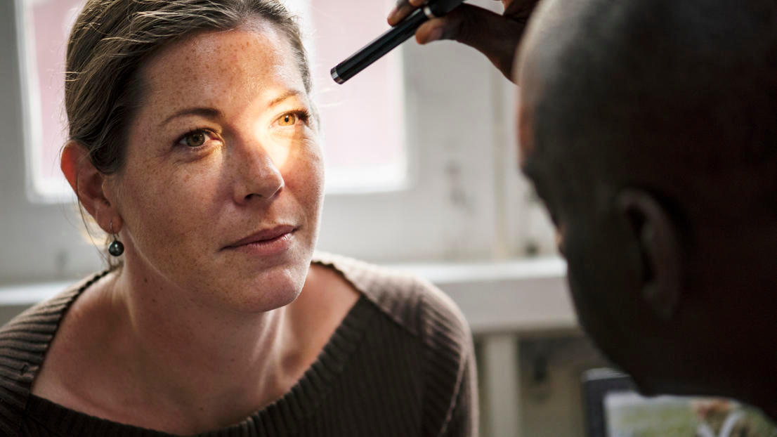 Blonde woman getting an eye examination with a small light tool
