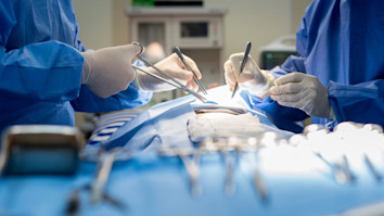 Two surgeons operating with tools in operating theatre
