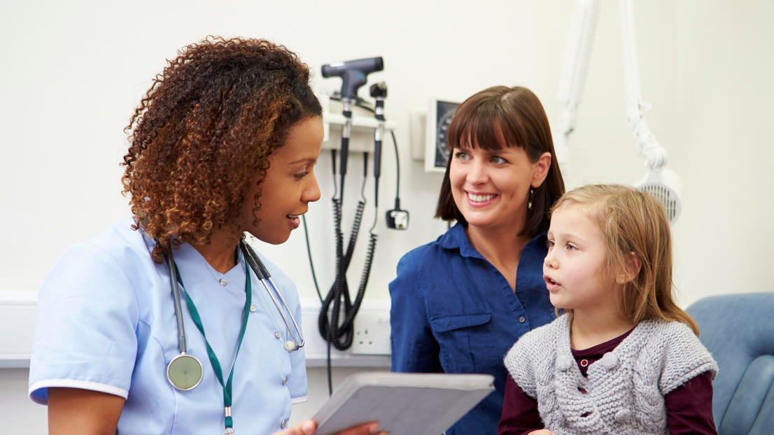 Parent with young child on lap with nurse during appointment