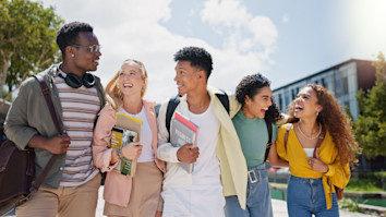 Students chatting and laughing on a university campus in the sunshine