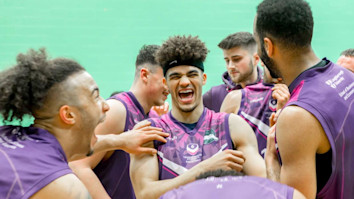 University basketball players smiling and laughing in a huddle