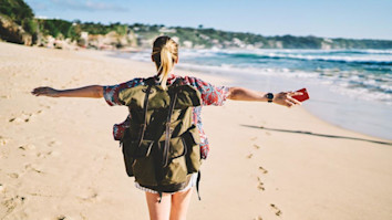 Blonde woman walking on sandy beach near the ocean