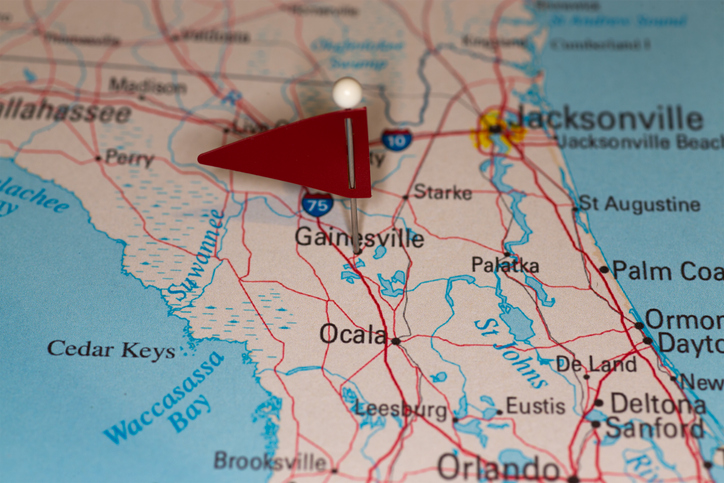 A pin marks Gainesville on a map of Florida, which also features several bodies of water and cities including Jacksonville and Orlando.