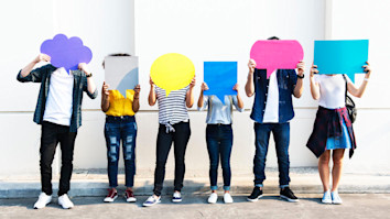 Six people holding up colourful placards that look like speech bubbles