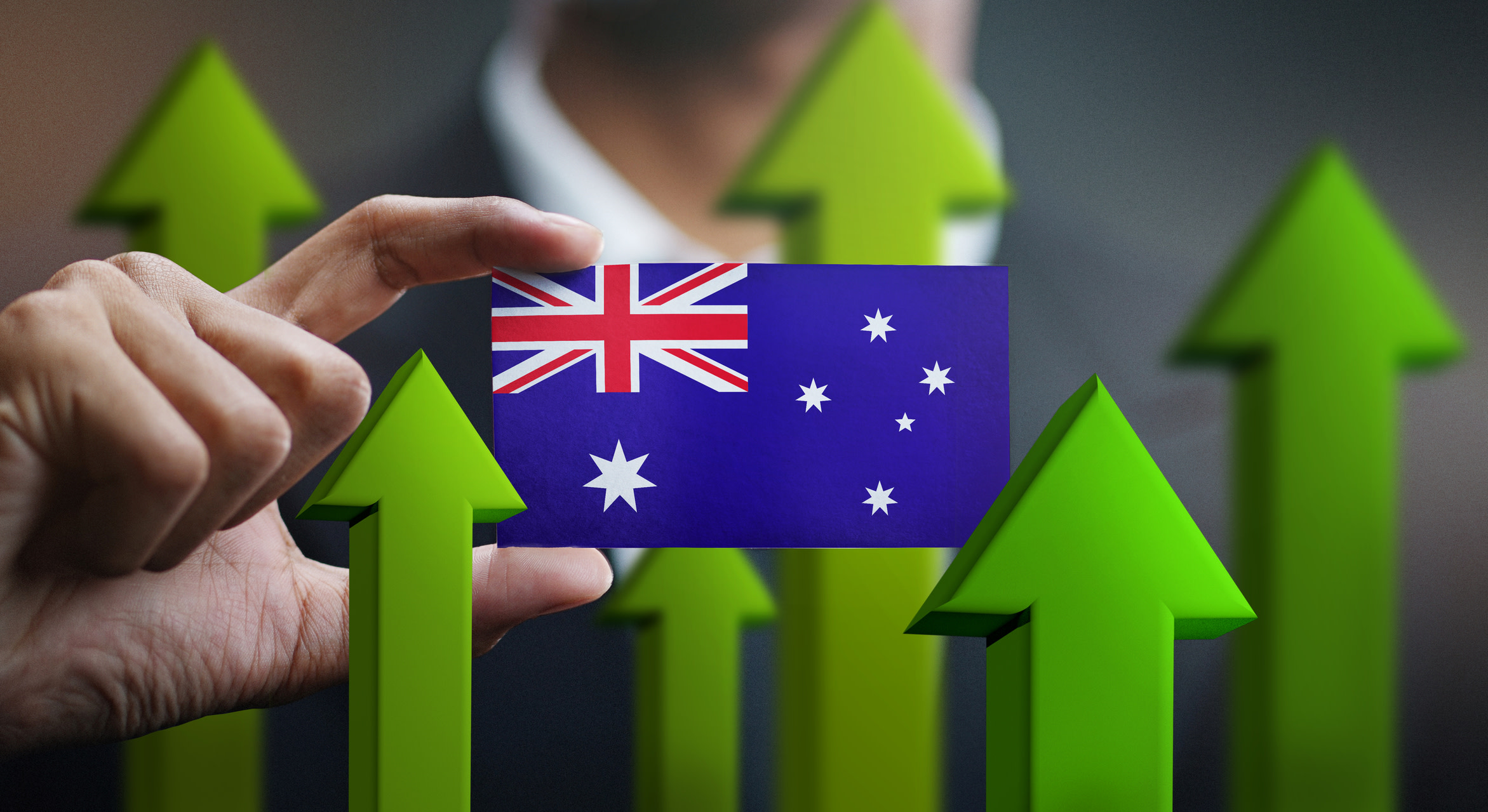 A man in a suit holds a small Australian flag in front of him, surrounded by upward-pointing green arrows