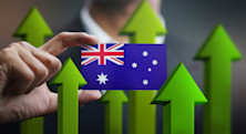 A man in a suit holds a small Australian flag in front of him, surrounded by upward-pointing green arrows