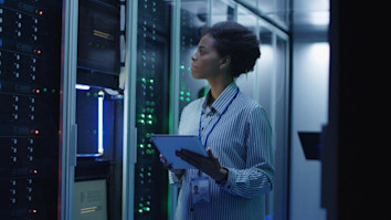 Woman working as IT engineer and standing among server racks in data centre