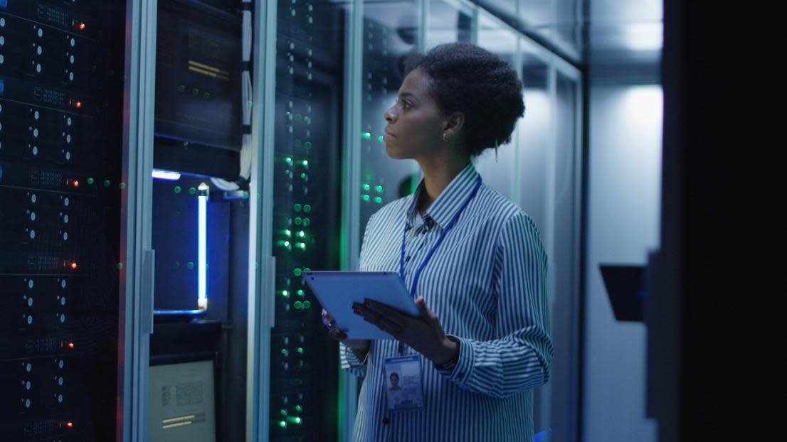 Woman working as IT engineer and standing among server racks in data centre