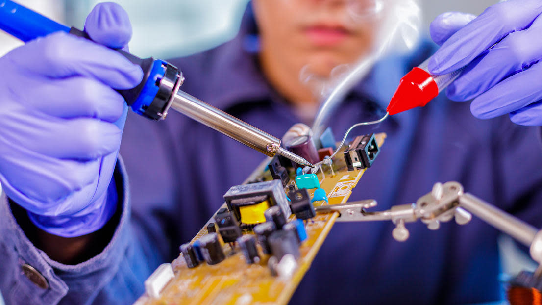 Engineer repairing electronic circuit board with soldering iron
