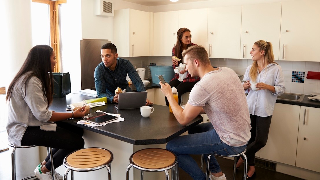Students relaxing in kitchen of shared accommodation