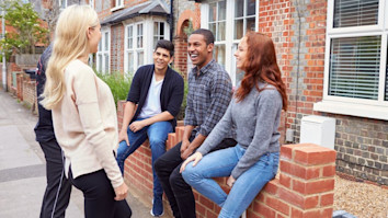 group of university students outside rented shared house talking