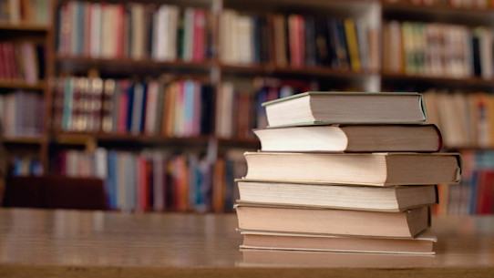 Books piled up on table in a library