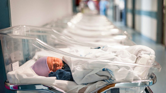 Newborn baby in first of many small hospital beds