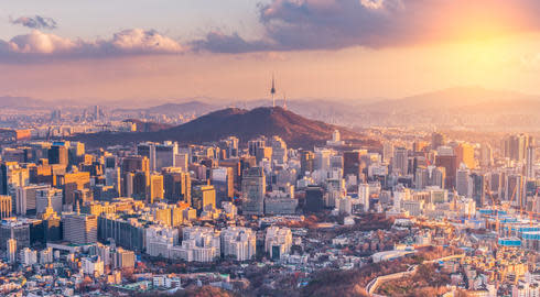 Sunset over the skyline of Seoul, South Korea, with many tall buildings visible ahead of the Namsan Tower on Nam Mountain