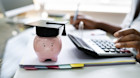 Woman applying online for student finance. A piggybank with a graduation cap is in the foreground