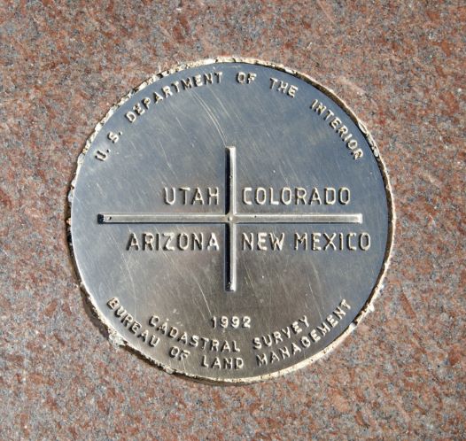 Metal plaque on the ground showing where the four states of Arizona, New Mexico, Utah and Colorado come together in one place. 