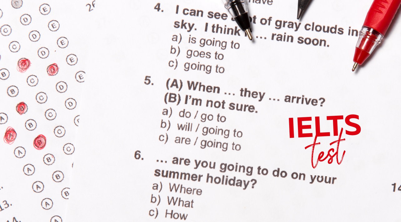 Three pens rest on top of an IELTS test paper
