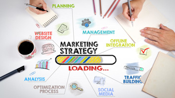 Marketing strategy mind map on white table chart with colourful keywords and hands writing on notebooks