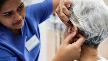 Nurse fitting and elderly person with a hearing aid