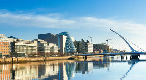 Samuel Beckett Bridge stands over the River Liffey in Dublin on bright, sunny day, with various modern buildings on the riverbank