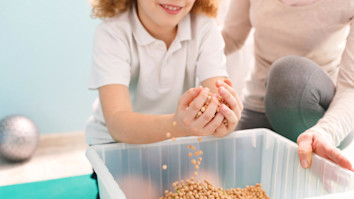 Child picking up chickpeas from a tub in hands