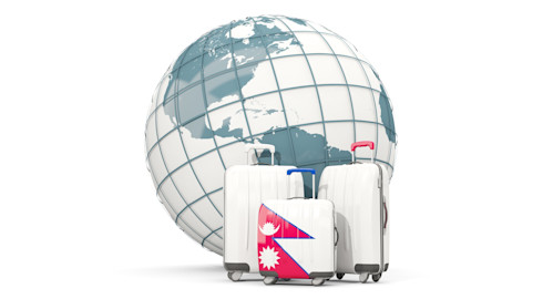 Three travel suitcases are placed in front of a globe. The smallest one features the flag of Nepal.