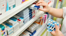 A pharmacist stocking pharmacy shelves with blister packs of tablets.