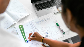 Student with teacher looking at engineering plans