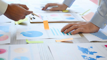 Two business people working on the office desk with graphs