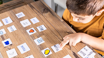 Little kid playing with cards of words and pictures