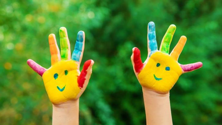 Child's hands painted with smiley faces