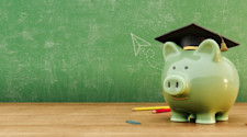 Green piggy bank wearing graduation hat in front of green chalkboard