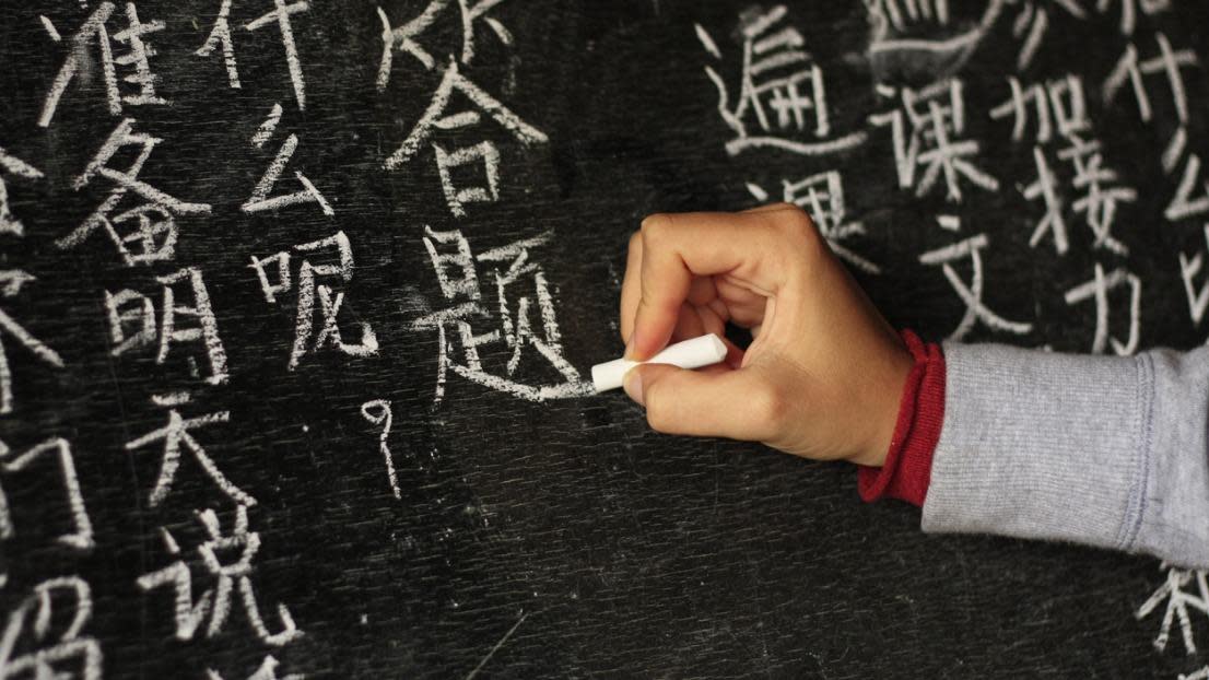 Girl writing Chinese characters on a blackboard