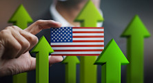A man in a suit holds a small American flag in front of him, surrounded by upward-pointing green arrows