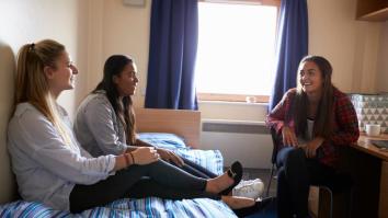 Students Relaxing In Bedroom Of Campus Accommodation