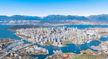 Aerial shot of Downtown Vancouver with mountains in the background and skyscrapers and bridges in the foreground.